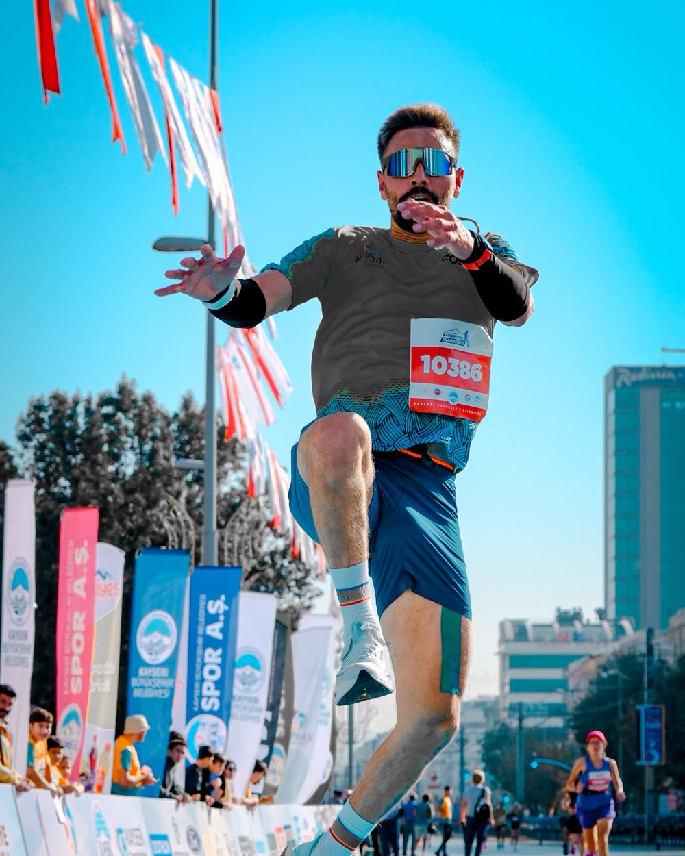 רץ באוויר בתחרות ריצה עירונית, על רקע דגלוני מסלול